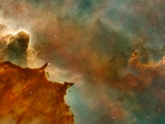 Photograph from NASA's Hubble Telescope of various gases, dust, and stars in orange, burnt orange, yellow, and teal