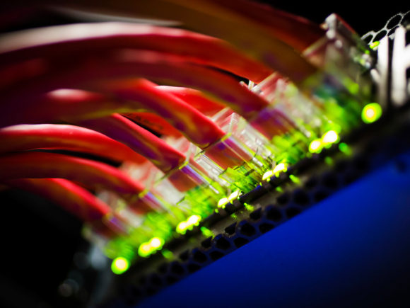 Red wires plugged into glowing green ports in a machine room at the National Center for Supercomputing Applications