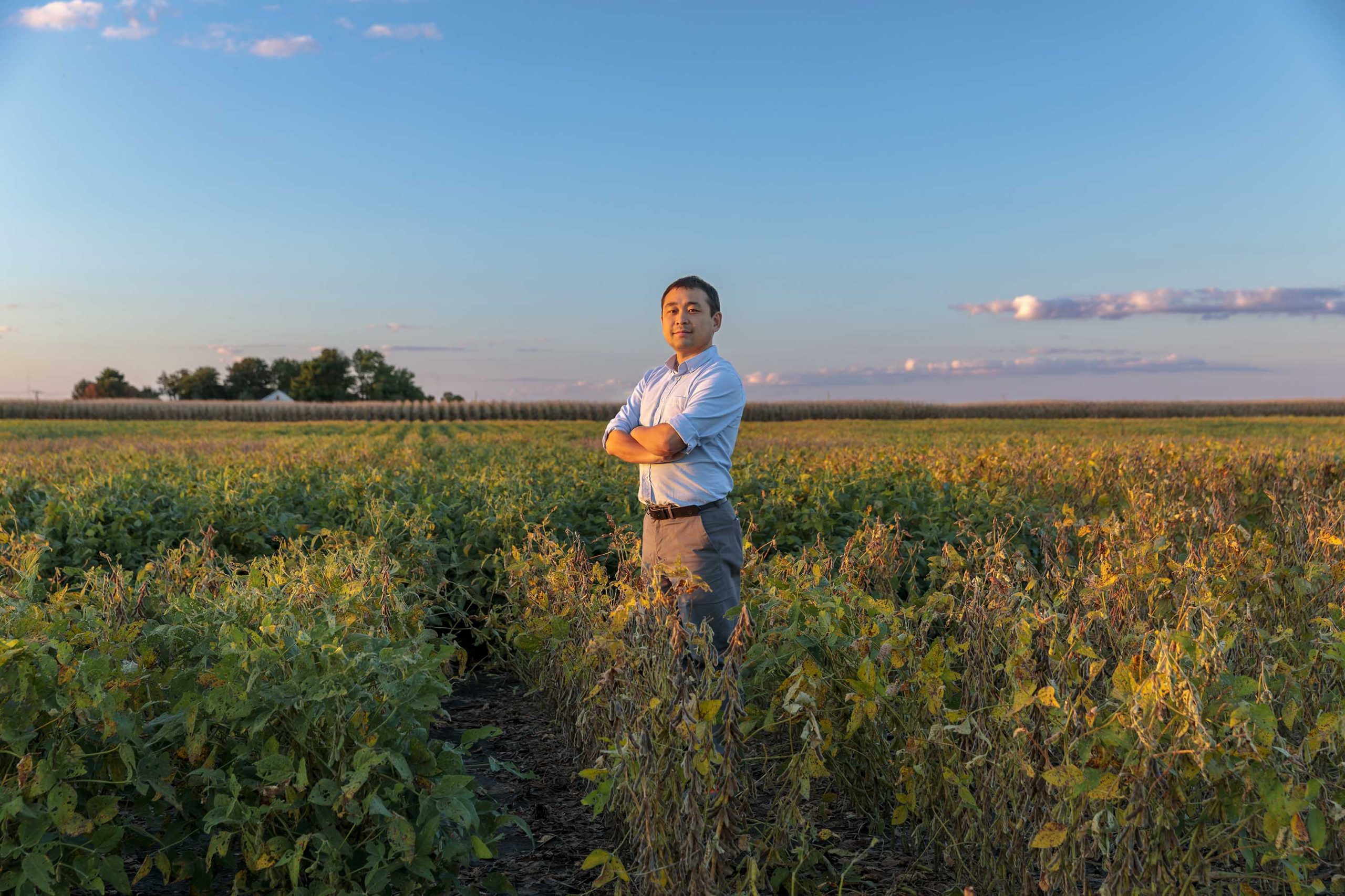 Kaiyu Guan standing in a field with his arms crossed while dressed in business attire