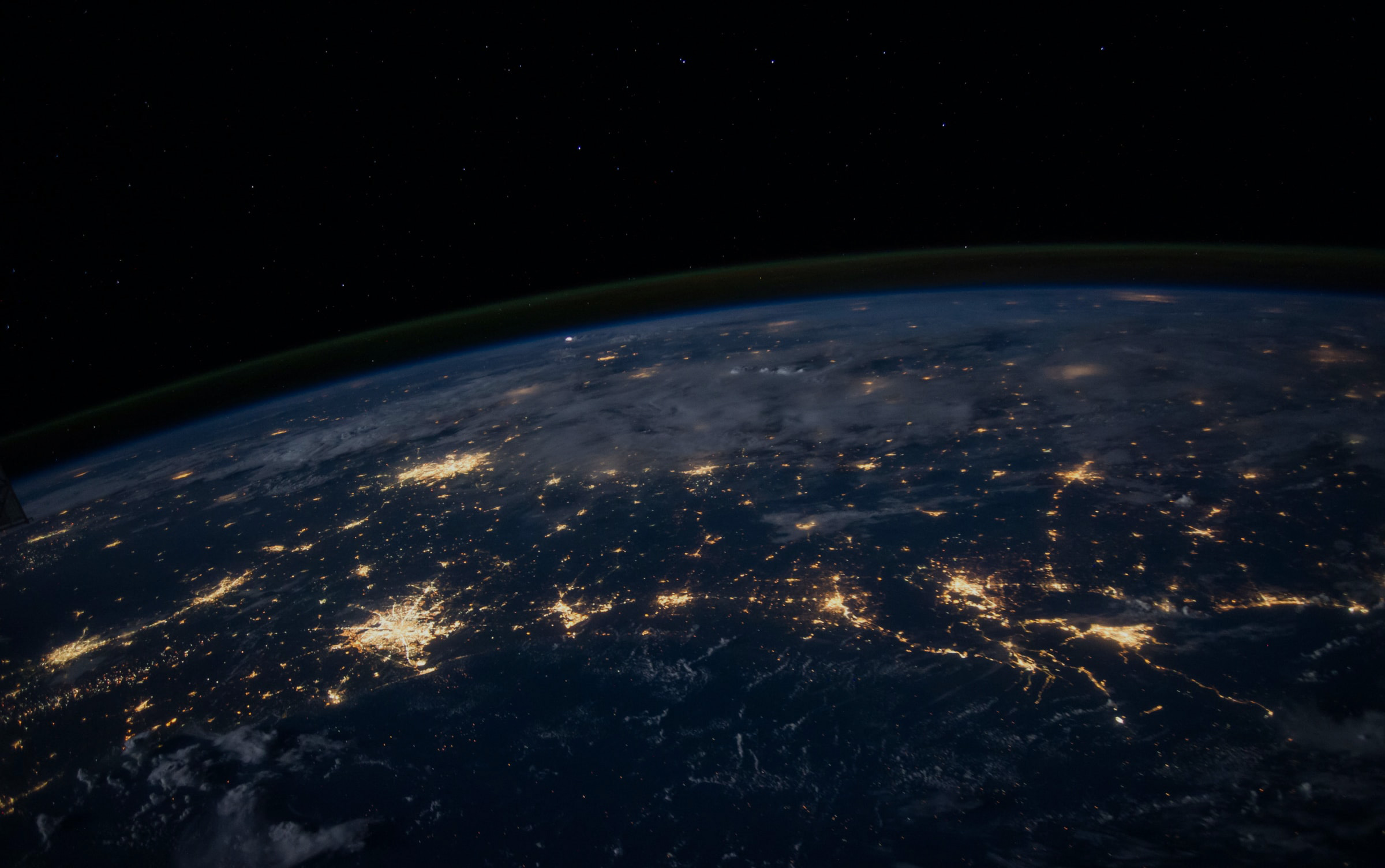 Night photograph of the Earth from space with lights indicating larger populated areas of the globe