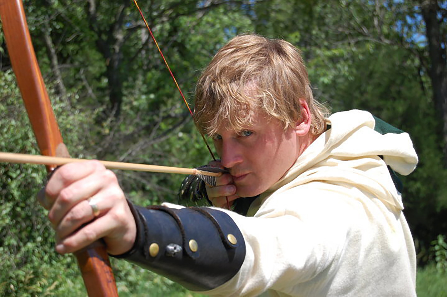 An image of Jeff in an archer costume, holding a bow and arrow, posing as if ready to shoot.