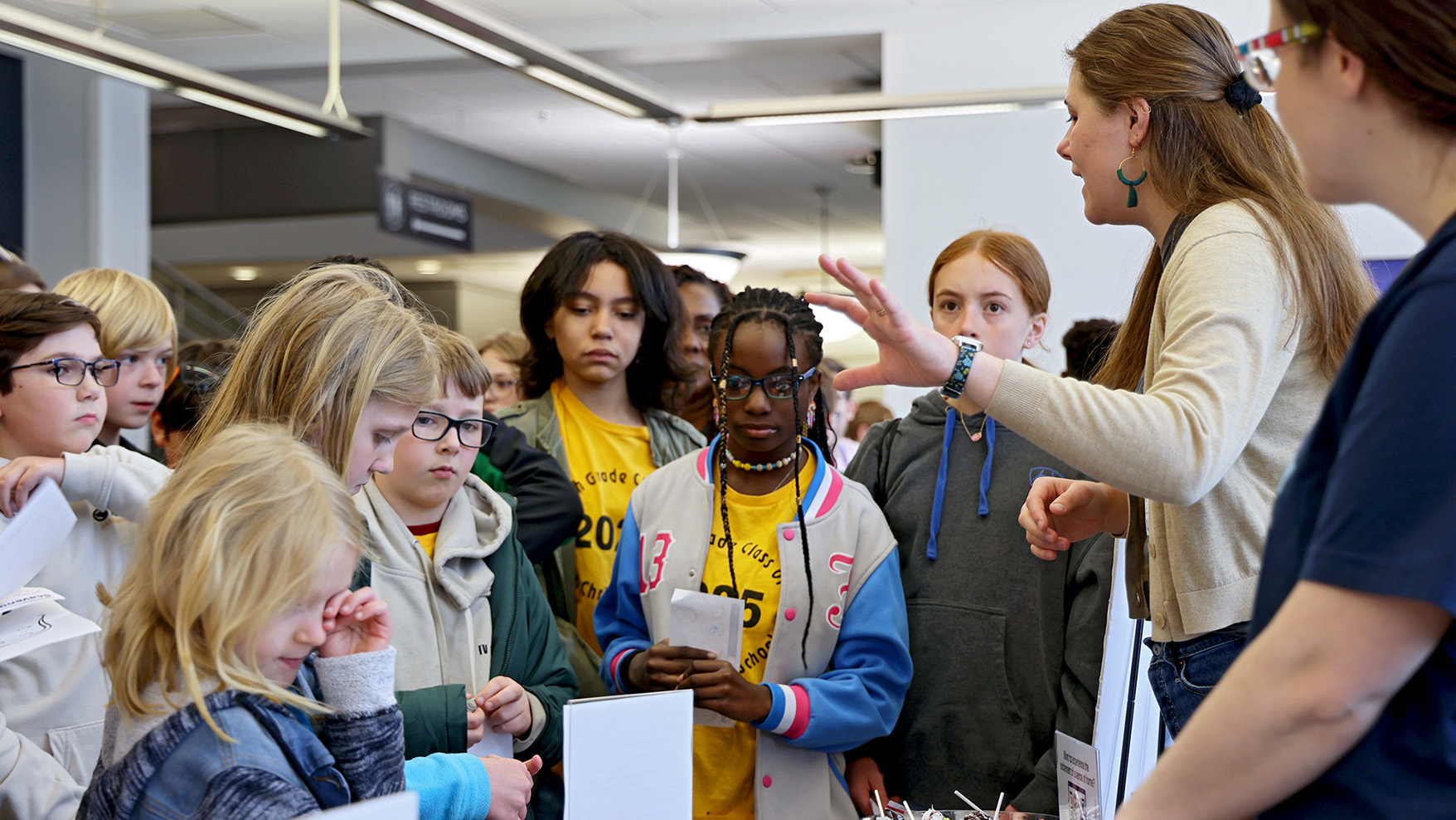Children gather around a presenter at the EOH conference to listen to her talk about research.