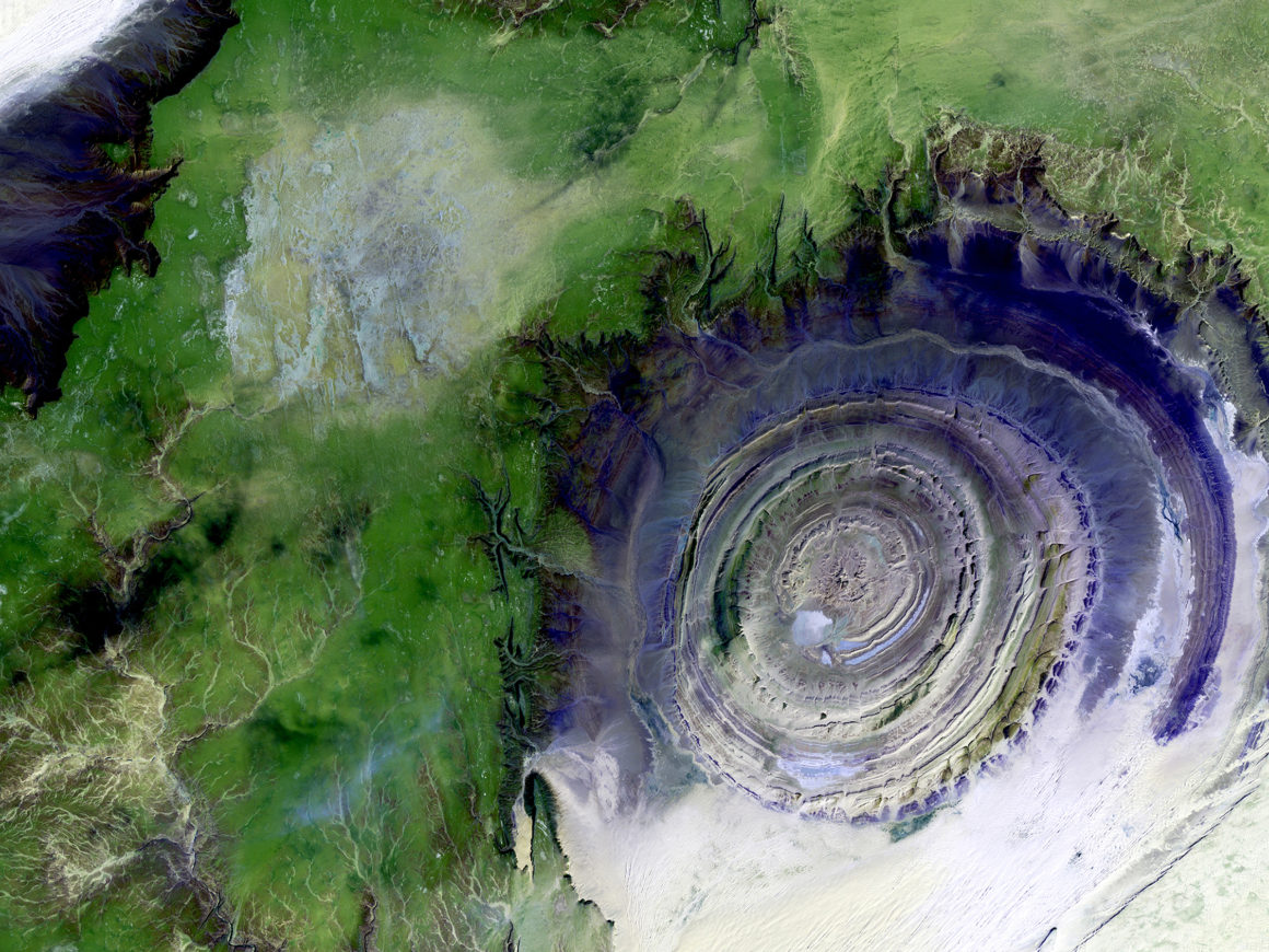 aerial photo of the Earth with forests, river tributaries, and a circular-shaped crater