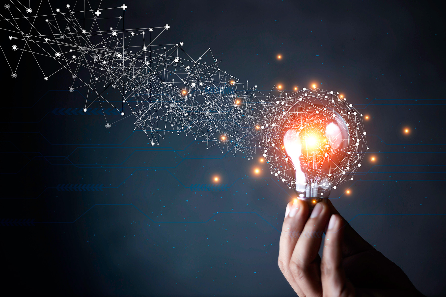 A hand holding a light bulb with connected dots flowing from the light. Meant to convey the idea of innovation and connections.